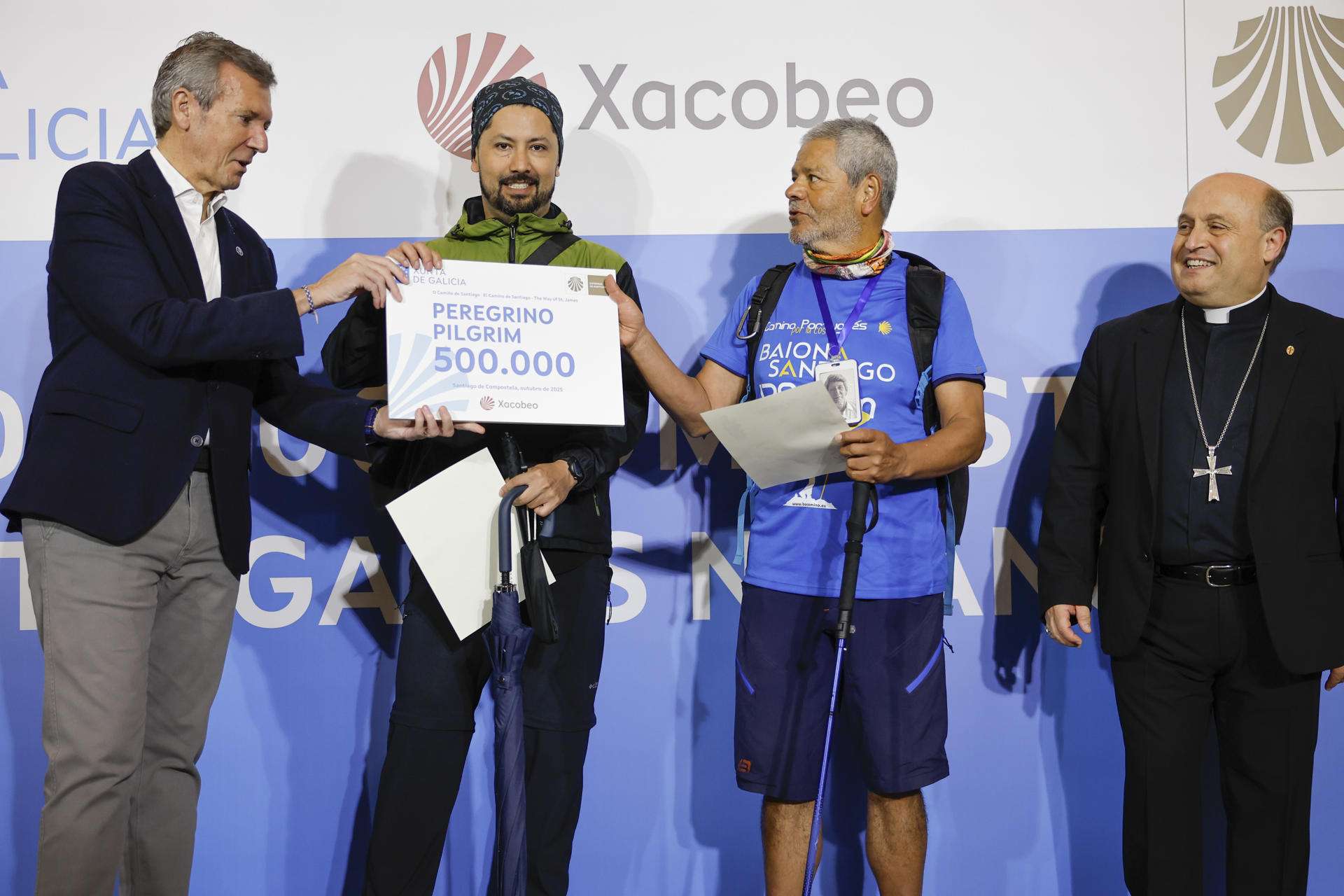 SANTIAGO DE COMPOSTELA, 20/10/2025.- El presidente de la Xunta, Alfonso Rueda (i), entrega la "Compostela" o certificado del peregrino 500.000 del año a los colombianos, Jairo Forero Chaves y su hijo Nicolás (2i), en presencia del arzobispo, Francisco Prieto, este lunes en Santiago de Compostela. EFE/Lavandeira jr.